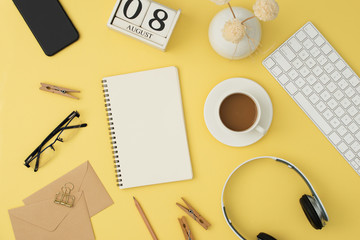 Mordern workplacewith keyboard, headphone, coffee, glassess, phone, pen on yellow background. Top view, flatlay.