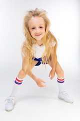 portrait of a young attractive athletic charming blond child in sportswear with hands posing on a white background