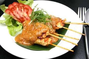 Thai chicken satay with peanut sauce on a white plate