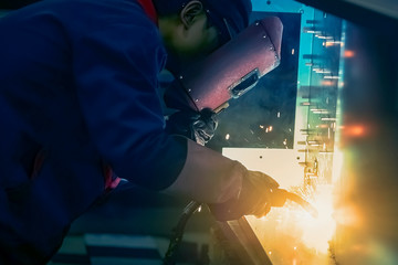 Worker doing spot welding in dim workshop