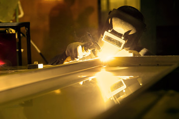 Worker doing spot welding in dim workshop