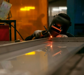 Worker doing spot welding in dim workshop