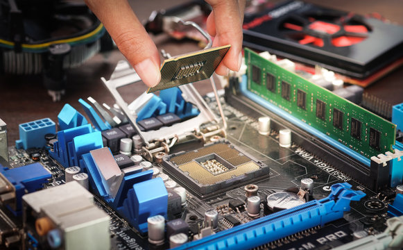 Engineers are placing the CPU on the sockets of the computer motherboard.