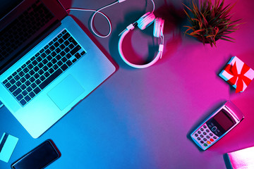 Laptop with headphones, phone, payment card, gift box and pin pad in neon colors. Concept of internet shopping