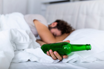 After drinking. Drunk bearded adult man lying on the bed and sleeping after drinking lots of...