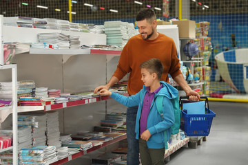 Little boy and father choosing school stationery in store