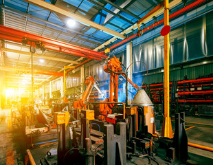 Large factory robotic arms are spraying sparks to weld car frames