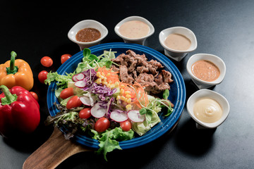 Traditional Italian food, Sliced grilled beef and organic vegetable salad with salad dressing on wooden plate have an appetizer dining in restaurant.