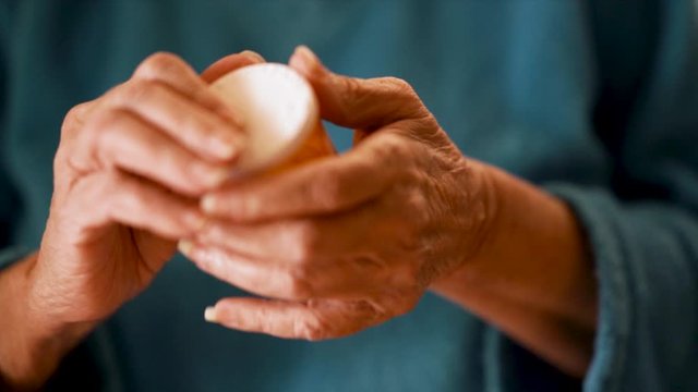 This slow motion footage is of the hands of a female senior citizen retrieving medicine pills from a container. Using f1.4 depth of field lens.
