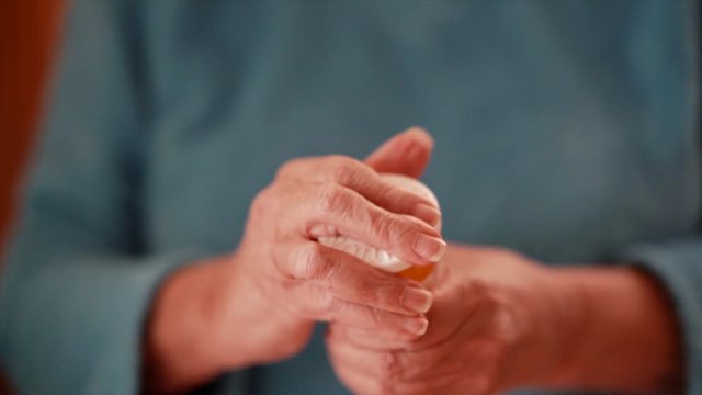 This slow motion footage is of the hands of a female senior citizen opening and retrieving medicine from a pill bottle. Very shallow depth of field.