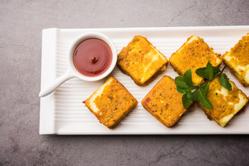 Amritsari Paneer Tikka made using cottage cheese cubes dipped in a batter made with besan, chat masala and spices and shallow fried in pan, served with ketchup