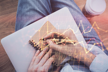 Double exposure of man doing notes of stock market with forex graph.