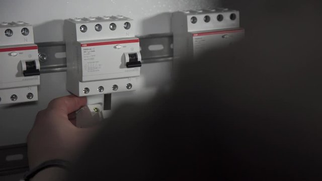 Close up of electrical switchboard with automats and wires. Stock footage. Man hands performing installation of electric shield.