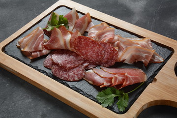Salami, prosciutto, bacon served with melon and mint on the cutting board. Italian lunch Delicatessen assortment of cold meat