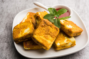 Amritsari Paneer Tikka made using cottage cheese cubes dipped in a batter made with besan, chat masala and spices and shallow fried in pan, served with ketchup