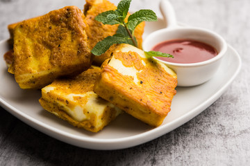 Amritsari Paneer Tikka made using cottage cheese cubes dipped in a batter made with besan, chat masala and spices and shallow fried in pan, served with ketchup