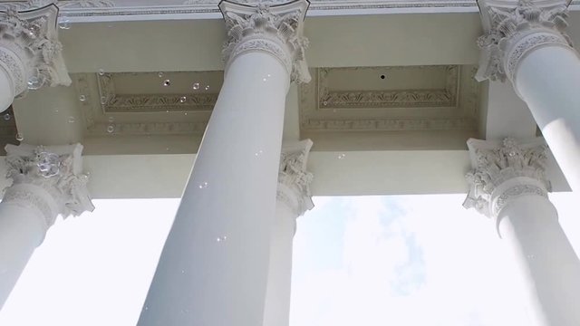 Many soap bubbles fly on the background of the classical portico with columns, constancy and variability, concept