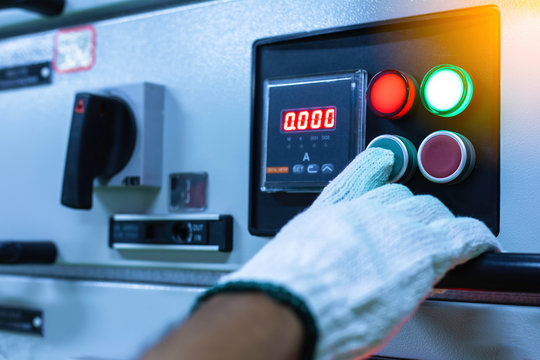Male hands holding the control panel of the industrial plant and pushing the button in Electrical selector switch,button switch,Electrical switch gear at Low Voltage motor control center cabinet .