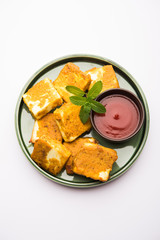 Amritsari Paneer Tikka made using cottage cheese cubes dipped in a batter made with besan, chat masala and spices and shallow fried in pan, served with ketchup