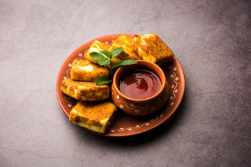 Amritsari Paneer Tikka made using cottage cheese cubes dipped in a batter made with besan, chat masala and spices and shallow fried in pan, served with ketchup