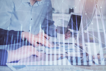 Multi exposure of chart with man typing on computer in office on background. Concept of hard work.