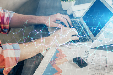 Double exposure of stock graph with businessman typing on computer in office on background. Concept...