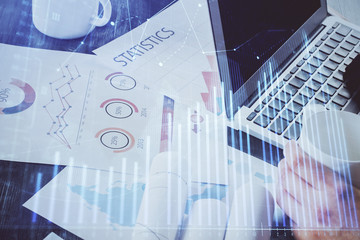Double exposure of stock graph with businessman typing on computer in office on background. Concept...
