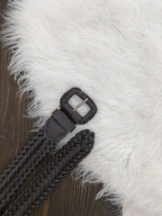 Dark brown leather braided belt on wooden background.