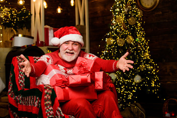 Obraz na płótnie Canvas Santa Claus relaxing in arm chair. Traditions concept. Santa Claus near christmas tree. Bearded senior man Santa Claus. Merry christmas. Elderly grandpa at home. Delivering gifts. Winter vacation