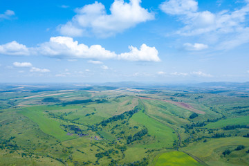 Landscape of green valley flooded with light with lush green grass, a fresh summer day under a blue sky with white clouds