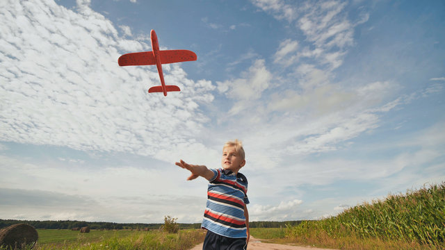 A little boy runs and launches a paralon toy airplane.