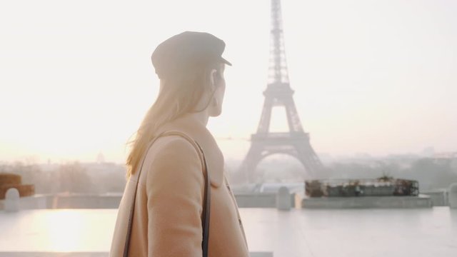 Cinematic track of happy brunette tourist woman walking along Trocadero, Paris near foggy Eiffel Tower slow motion.
