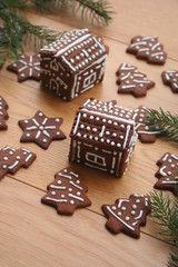 Christmas background. Homemade Christmas chocolate cookies in shape of little houses and trees on a wooden table with pine branches