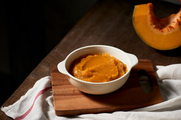 Pumpkin puree in a bowl on wooden background