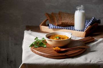 Roasted pumpkin and carrot soup with cream and toast on wooden background. Copy space
