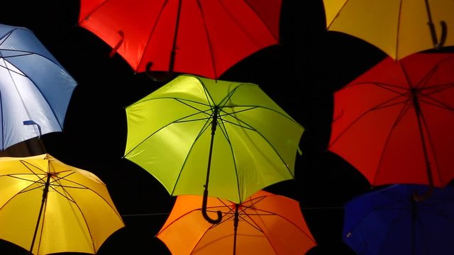 Vivid umbrellas at night, on the street, above on wires. Artistic installation,