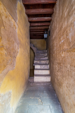 Day shot of old narrow passage with stone staircase and wooden ceiling
