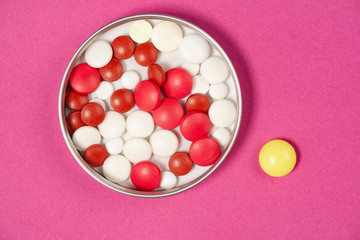 Medical pills in a tin on pink background.