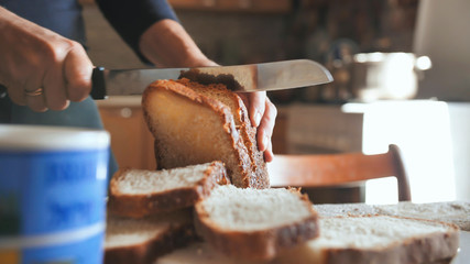Cooking breakfast. A young woman cuts bread.