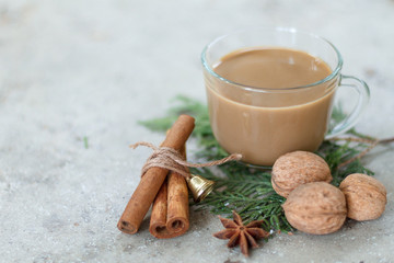 Cup of coffee, walnuts, cinnamon sticks and anise stars on a green branch of cypress. New Year's...