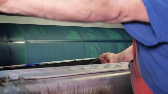 Worker takes off printing plates in press factory