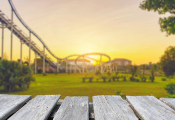 Empty wooden table top on the blur background of roller coaster in amusement park