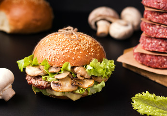 sandwich with meat and mushrooms on a wooden board on a black background next to the ingredients