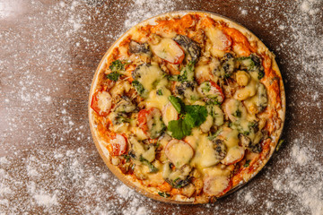 Hot big pizza pizza composition with melting cheese chicken tomatoes mushrooms steam smoke on a black background