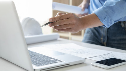 Architect or Engineer working in office with engineering tools, blueprint and building model. Construction concept.