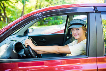 Fototapeta na wymiar Happy smiling woman driver behind the wheel red car