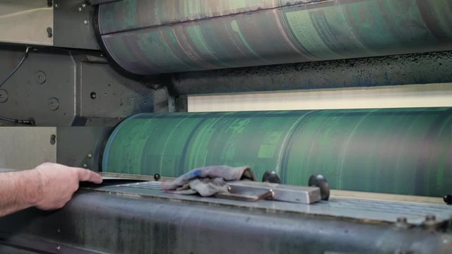 Worker installs new printing plates at the ink rollers of press machine