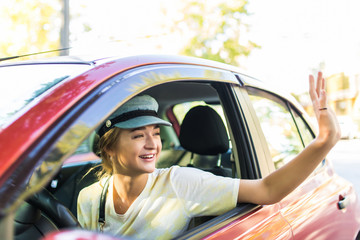 Young woman drive her car greeting with hands