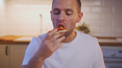 Portrait of a young beautiful man eating a slice of pizza