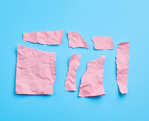 set of various cut pieces of pink crumpled paper on a blue background
